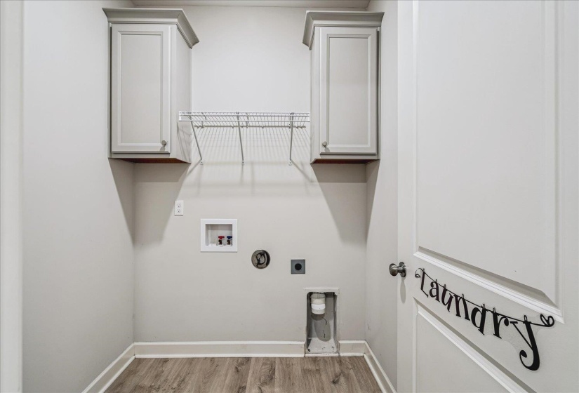 Dedicated laundry area featuring wood-finish flooring, light gray wall paint, and white baseboards