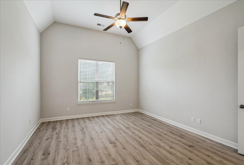 Vaulted ceiling room featuring a ceiling fan, wood-finish flooring, a window with blinds, and white baseboards