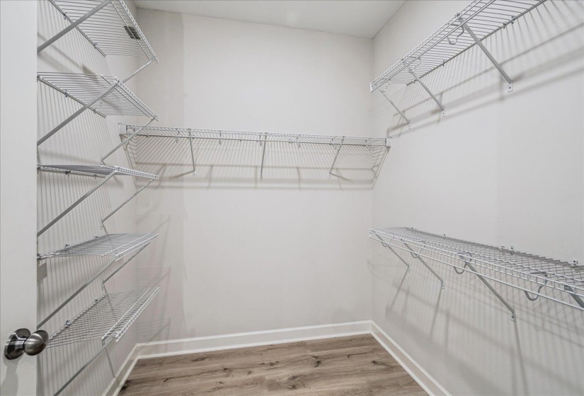 Walk-in closet featuring light wood-finish flooring, white baseboards, and comprehensive wire shelving systems