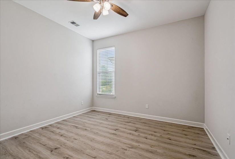 Neutral color palette with wood-finish flooring, a window with horizontal blinds, and a ceiling fan