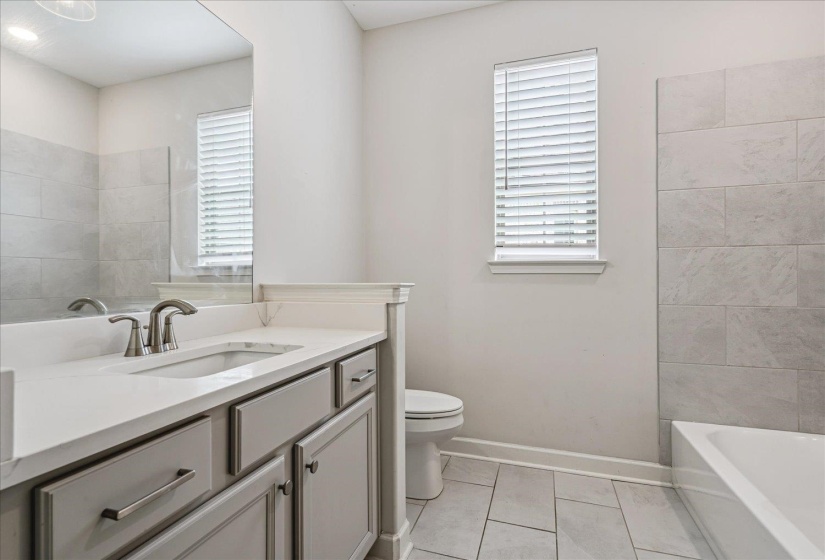 Bathroom featuring a single vanity with stone-finish countertop, undermount sink, and brushed nickel faucet