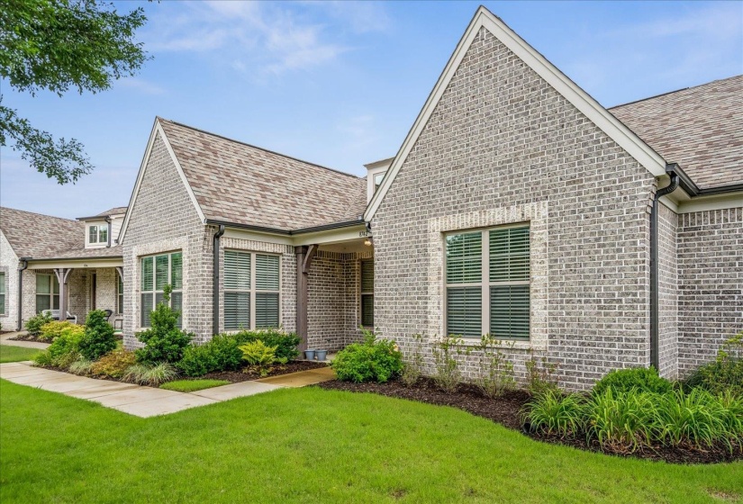 Grey brick exterior featuring white trim accents, multiple gables, and a shingled roof