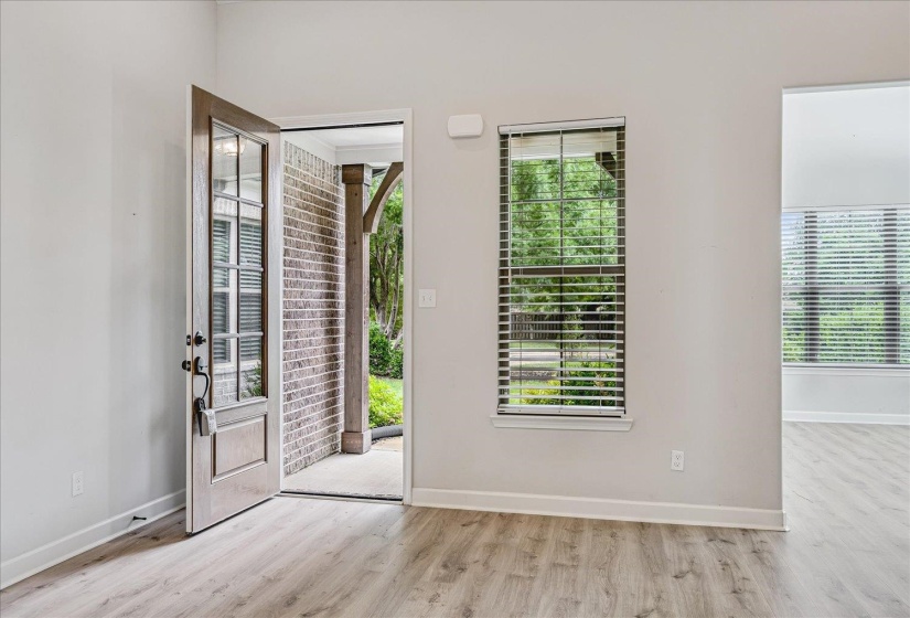 Entryway with wood-finish flooring, a glass-paned front door, and a brick-accented porch