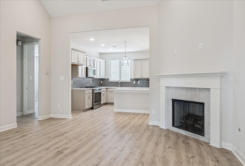 Spacious open-concept interior featuring light wood-finish flooring and vaulted ceilings