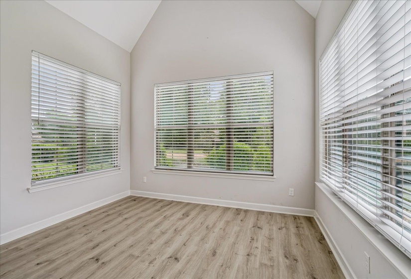 Bright room with vaulted ceilings, wood-finish flooring, and multiple windows with blinds