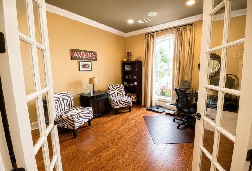 French doors open to a versatile room featuring wood-finish flooring, an arched window, crown molding, and recessed lighting