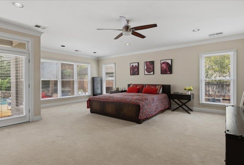 Spacious room featuring neutral carpeting, a ceiling fan with integrated lighting, recessed lighting, crown molding, and multiple windows with blinds