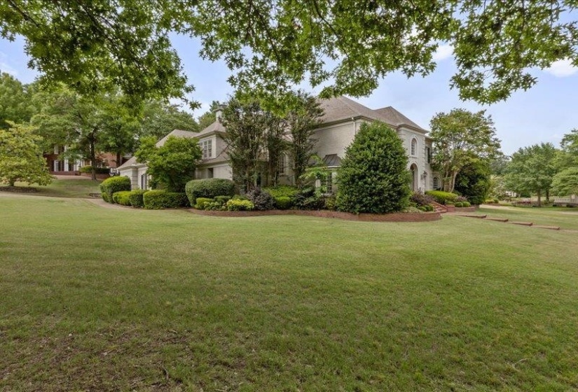 Stately residence featuring a light-colored exterior, multiple gables, and a prominent arched window