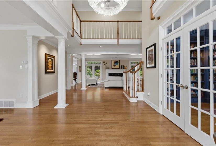 Two-story foyer with hardwood flooring, a coffered ceiling, and a prominent chandelier