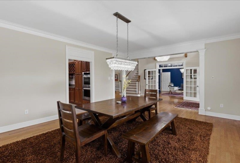 Formal dining area featuring hardwood flooring, extensive crown molding, and a tiered crystal chandelier