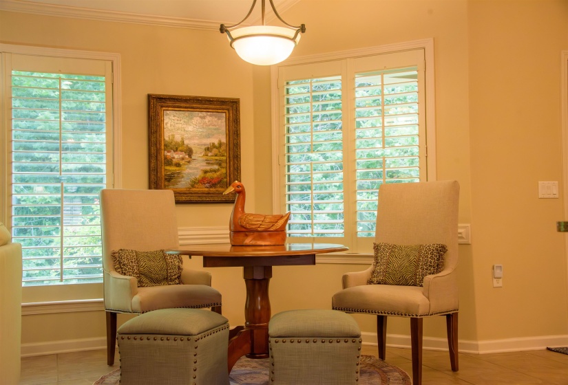 Breakfast nook featuring two large windows with louvered shutters, crown molding, and a semi-flush mount ceiling light