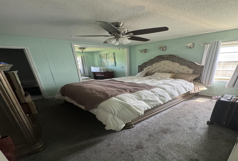 Room featuring wall-to-wall carpeting, light-colored wall paneling, and an overhead ceiling fan with integrated lighting