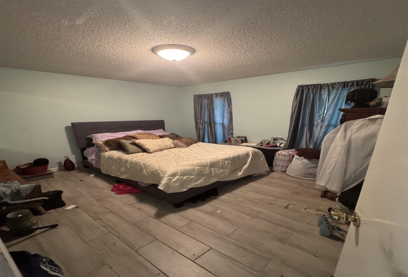 Spacious room featuring wood-finish flooring, two window openings, and a ceiling-mounted light fixture