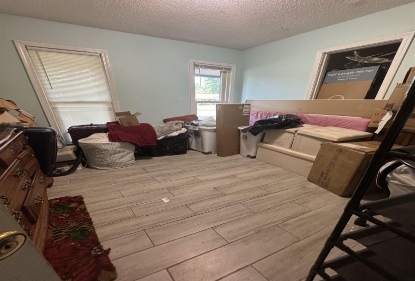 Room featuring wood-finish flooring, two windows with blinds, and light blue wall paint