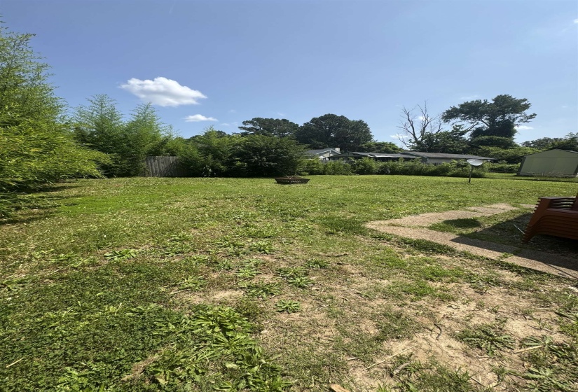 Expansive green space featuring mature perimeter foliage and concrete paver accents