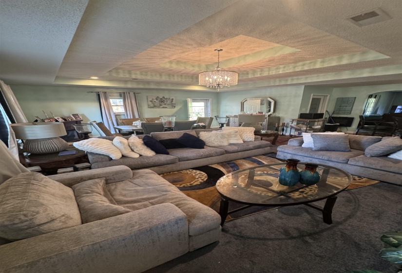 Recessed lighting and a decorative chandelier illuminate the tray ceiling