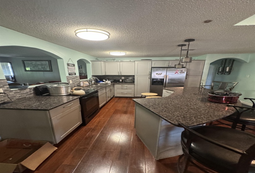 Kitchen featuring wood-finish flooring, light gray cabinetry, dark speckled countertops, and a full suite of stainless steel appliances