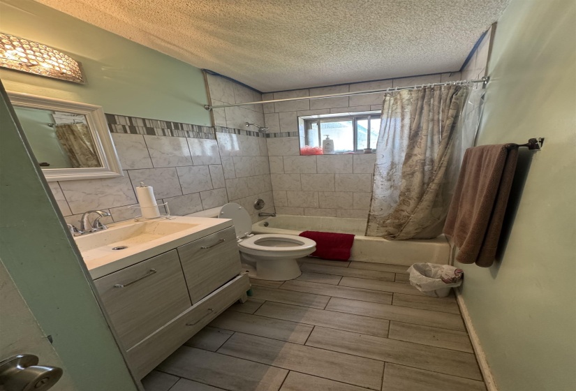 Bathroom featuring a light wood-finish vanity with an integrated sink, chrome faucet, and mirrored cabinet