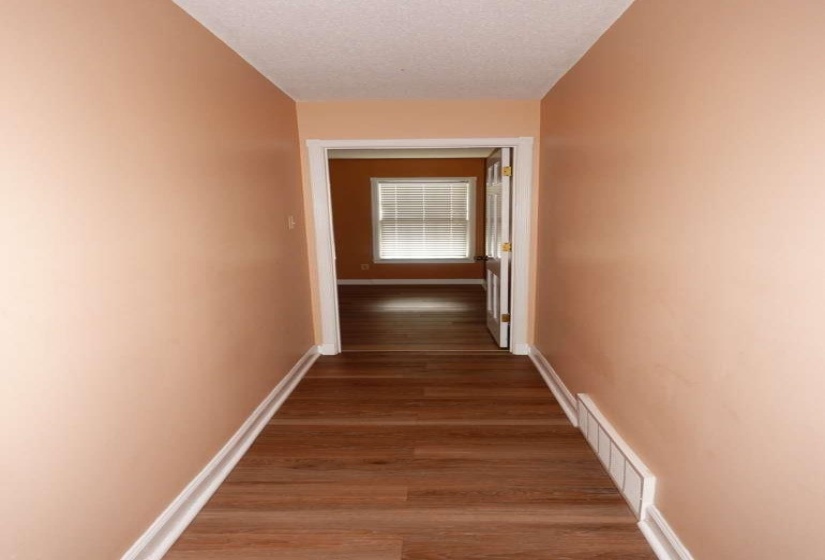 Hallway featuring wood-finish flooring and light peach wall paint