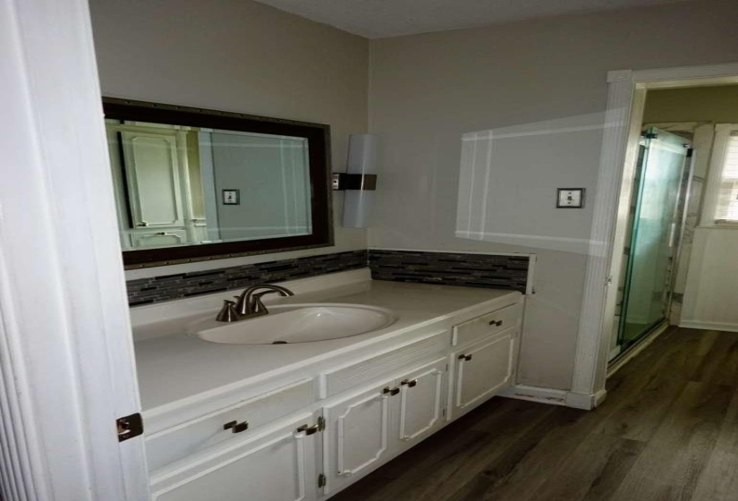 Bathroom featuring a single vanity with a white countertop, undermount sink, and brushed nickel faucet