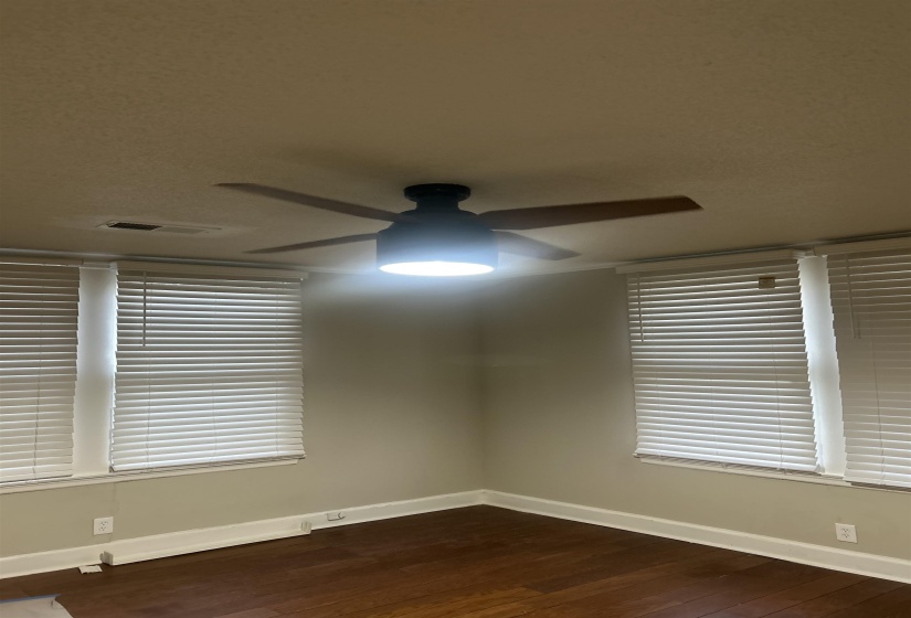 Bedroom ffeaturing wood blinds,ceiling fan, and wood floors