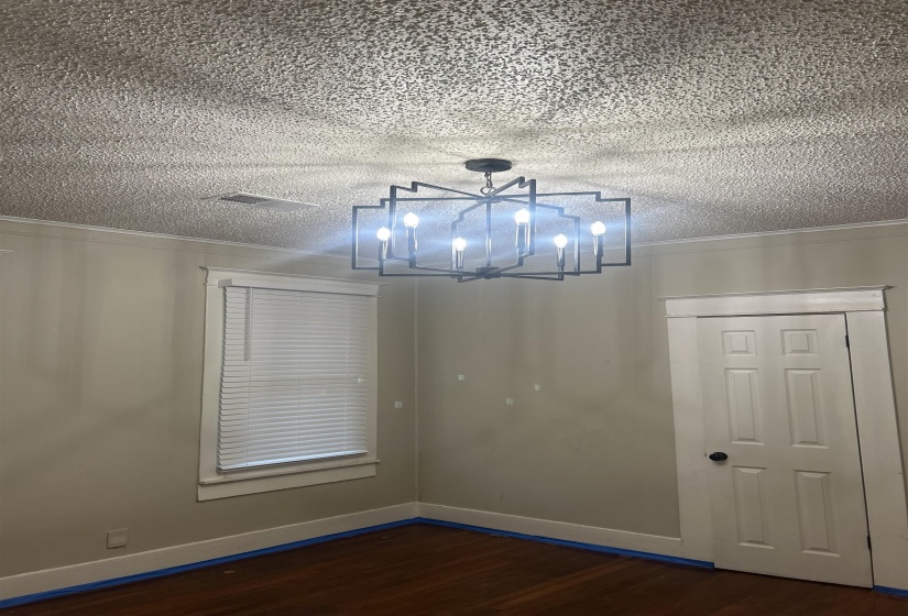 Unfurnished room with crown molding, dark wood-type flooring, a textured ceiling, and a chandelier