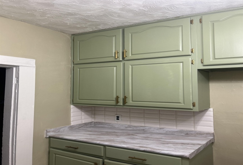 Kitchen featuring green cabinetry, decorative backsplash, and light countertops