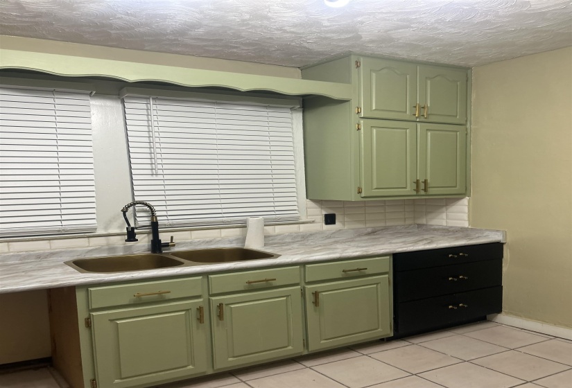 Kitchen featuring green cabinets, light countertops, light tile patterned floors, and a textured ceiling