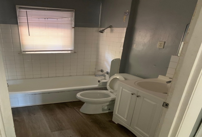 Full bathroom with hardwood / wood-style floors, vanity, toilet, and tiled shower / bath combo