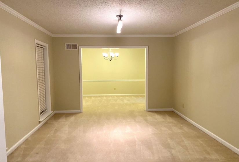 Unfurnished room with ornamental molding, a chandelier, a textured ceiling, and carpet