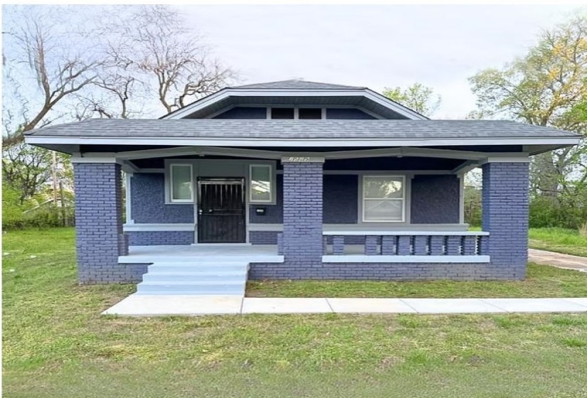 View of front of house with a porch, brick siding, and a front yard