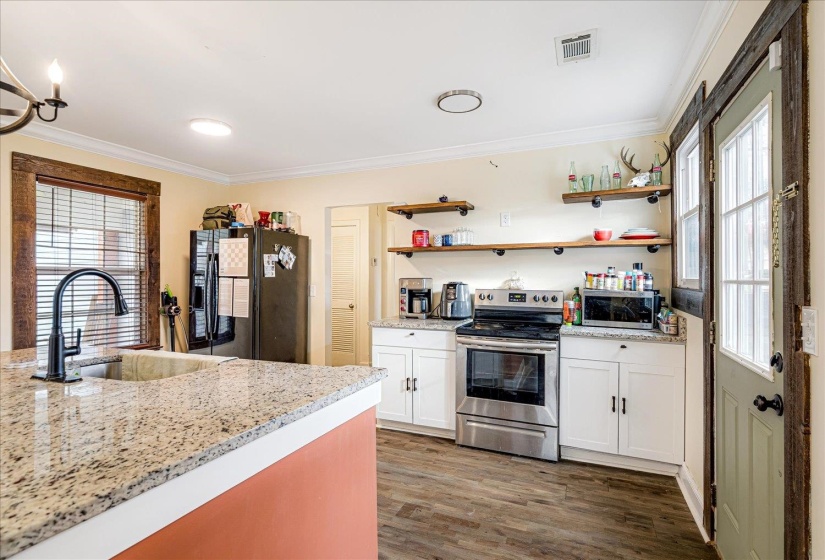 Kitchen featuring light stone countertops, stainless steel appliances, ornamental molding, dark wood-style flooring, and white cabinets