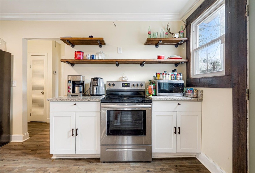 Kitchen featuring stainless steel appliances, open shelves, white cabinets, light stone counters, and crown molding