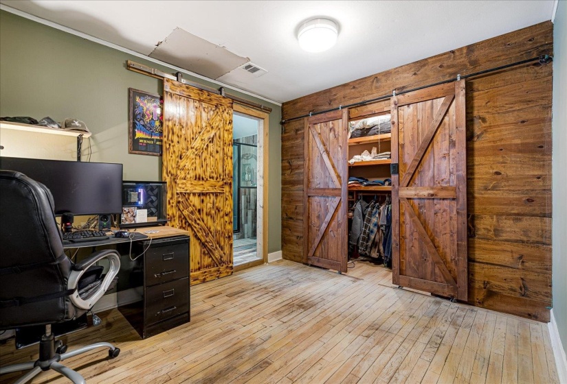 Home office featuring a barn door, wood walls, and light wood finished floors
