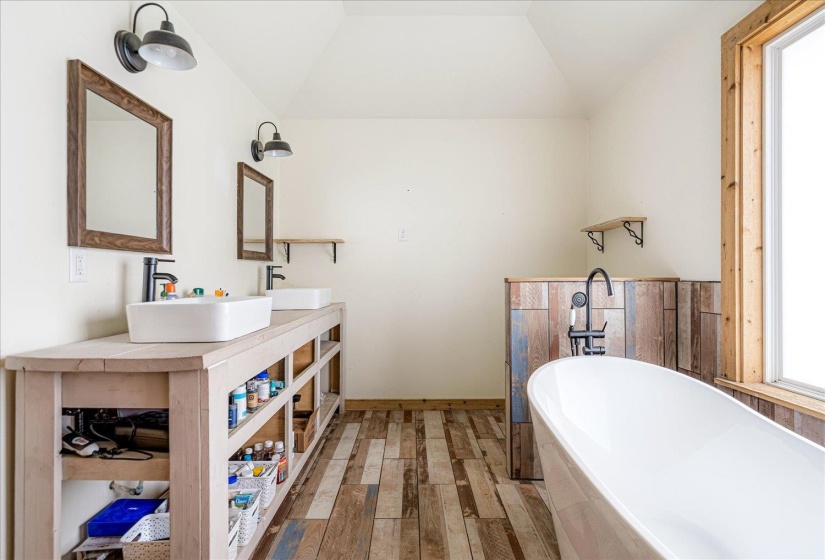 Full bathroom with light wood finished floors, double vanity, a soaking tub, plenty of natural light, and vaulted ceiling