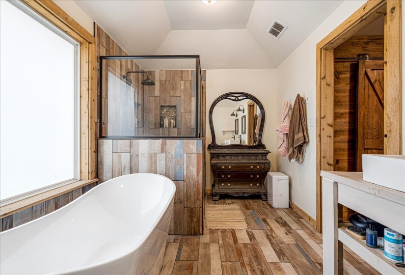 Full bath with wood finished floors, vaulted ceiling, a freestanding bath, vanity, and a walk in shower