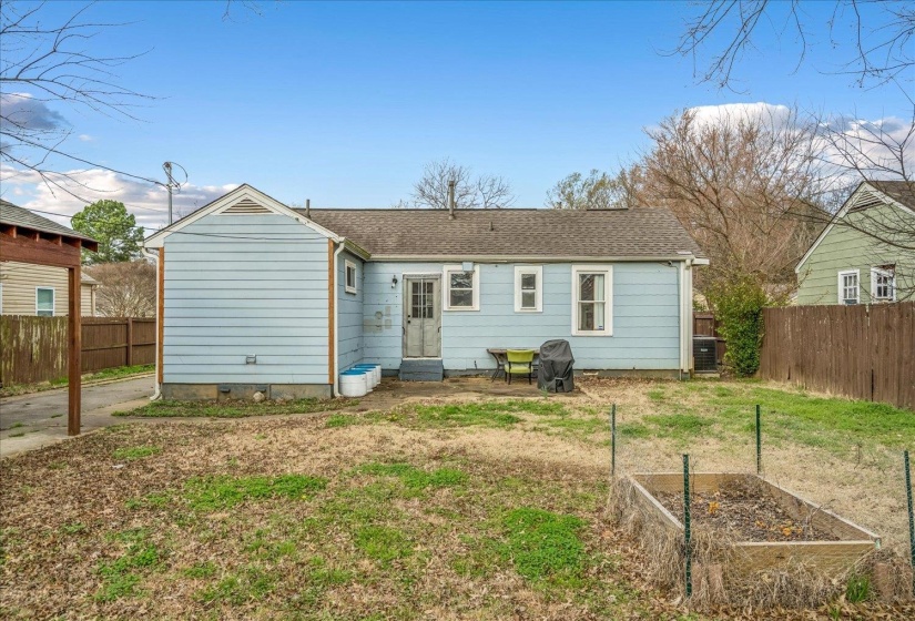 Back of property featuring a fenced backyard, a patio, roof with shingles, and a garden