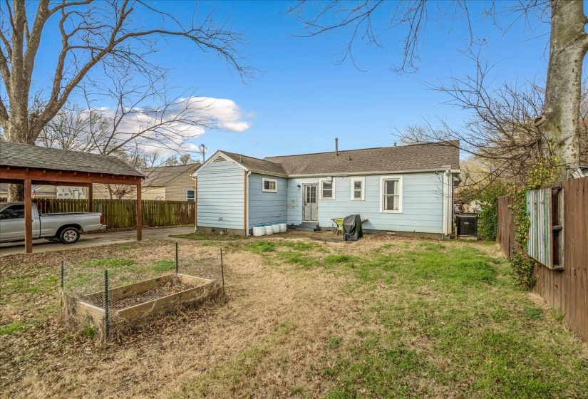 Back of house featuring a vegetable garden, a fenced backyard, and entry steps