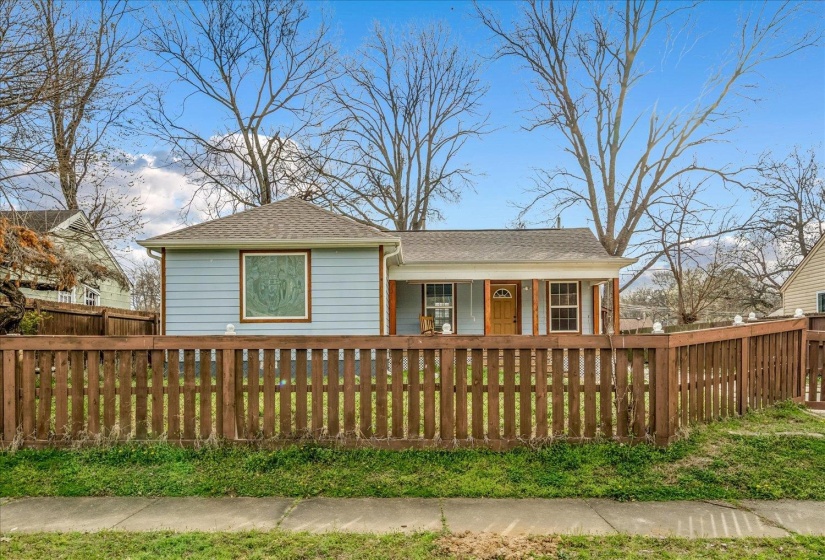 View of front facade featuring a fenced front yard, roof with shingles, and a porch
