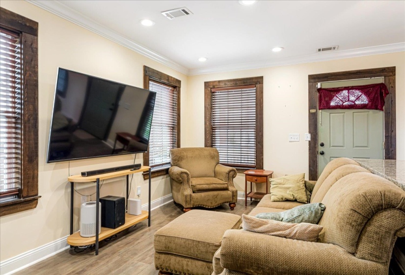 Living area with wood finished floors, recessed lighting, and ornamental molding