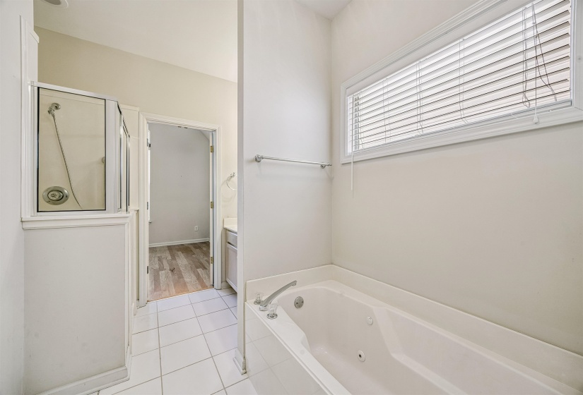 Soaking tub with chrome fixtures, accompanied by a glass-enclosed shower with a chrome showerhead