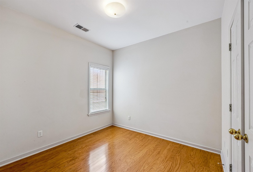 Room with wood-finish flooring, a single window with blinds, and a flush mount ceiling light