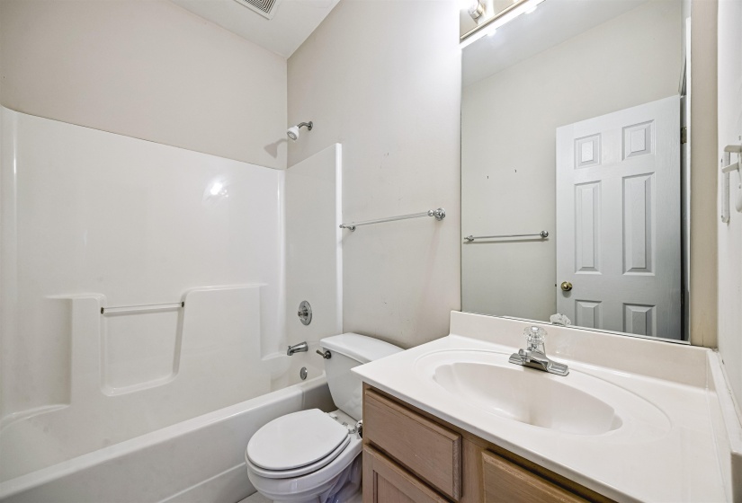 Bathroom featuring a white integrated sink with laminate countertop, natural wood-finish vanity, and chrome faucet