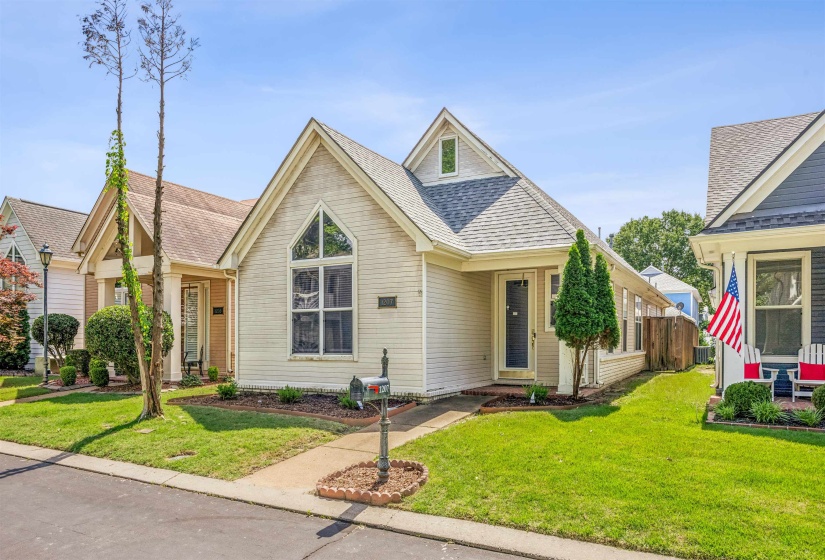 Single-story residence featuring light-colored siding, a prominent arched window with white trim, and a gabled roofline