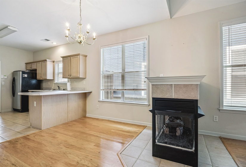 Fireplace with tile surround, wood-finish flooring, and recessed lighting