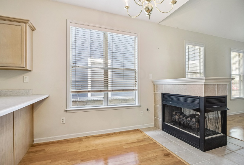 Hardwood flooring complements a corner fireplace with a tiled hearth and mantel