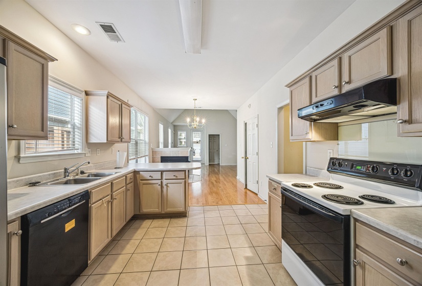 Kitchen featuring tile flooring, light-toned cabinetry, a double basin sink, black appliances, and a pass-through counter