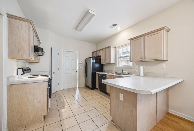 Kitchen featuring light wood-finish cabinetry, light-toned countertops, and a white tile floor