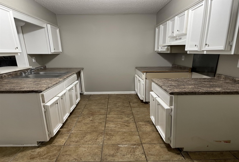 Kitchen with white cabinetry, dark countertops, a textured ceiling, and under cabinet range hood
