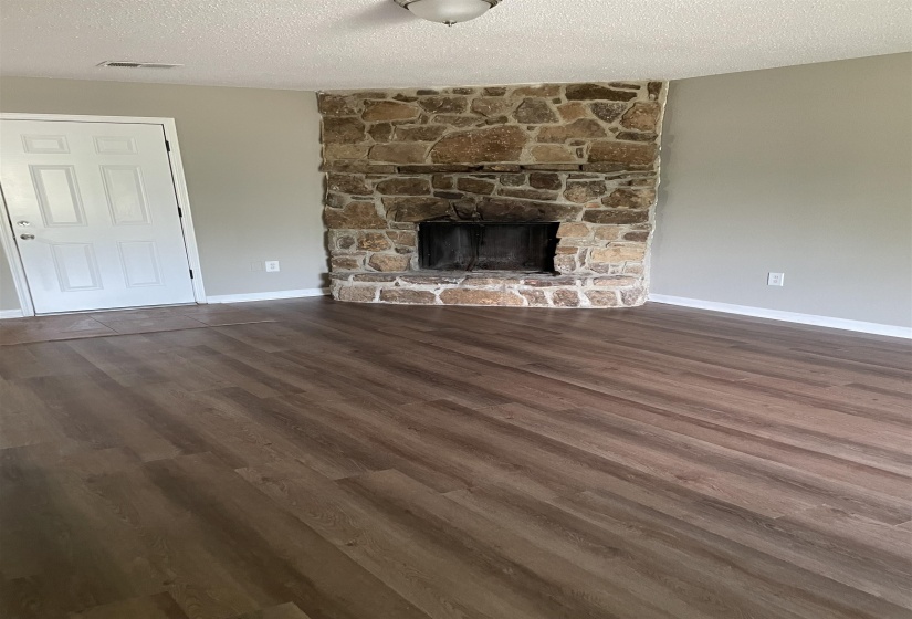 Unfurnished living room with a textured ceiling, a fireplace, and dark wood finished floors
